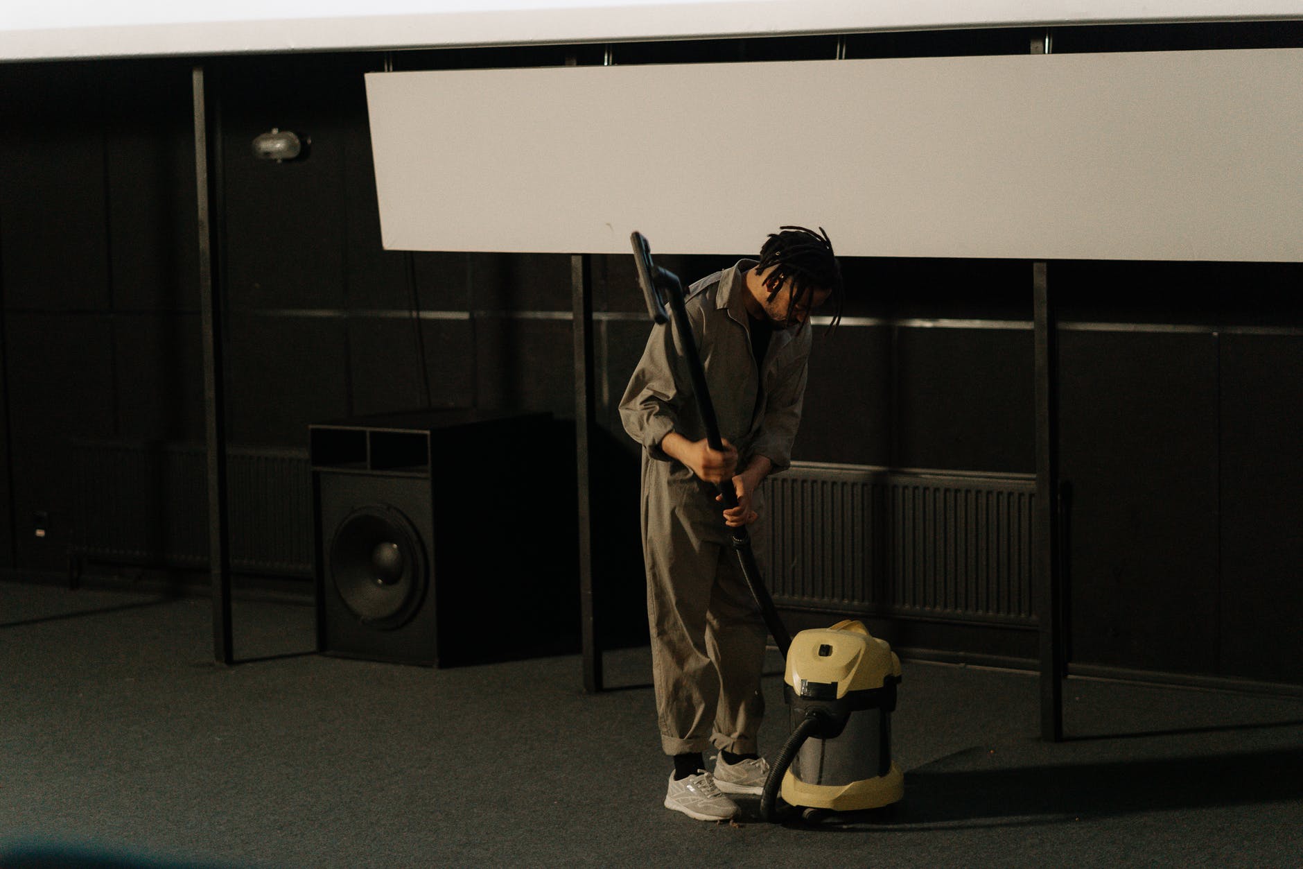 a man holding a vacuum cleaner near a speaker