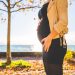 pregnant woman wearing beige long sleeve shirt standing near brown tree at daytime