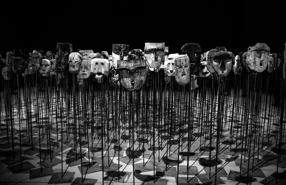 greyscale photo of masks on a stick