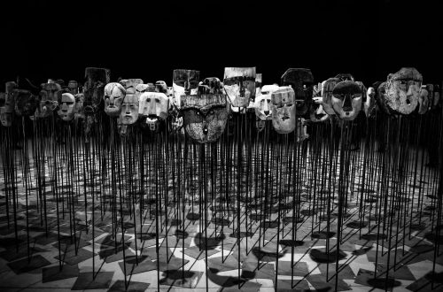 greyscale photo of masks on a stick