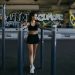 woman in black sports bra and black shorts holding on l parallel bars